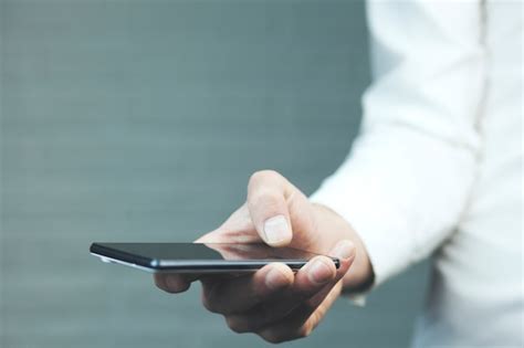 Masculino Mão Segurando O Telefone Inteligente Móvel Em Branco Foto