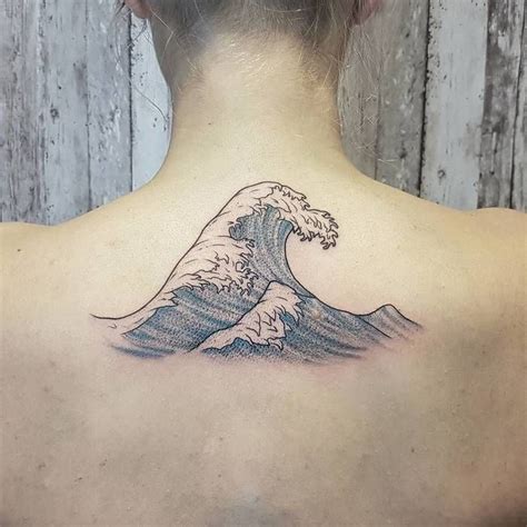 The Back Of A Womans Neck With A Tattoo Of A Wave On It