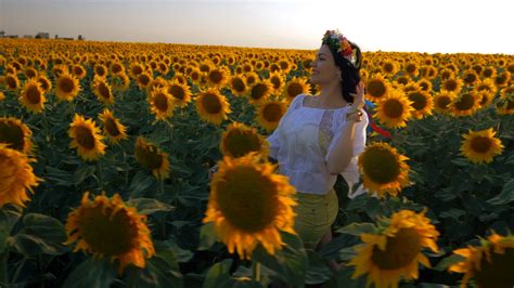 Beautiful Girl With Wreath Running On Yellow Sunflower Field Raising
