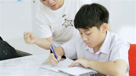 Slow Motion Of Asian Mother Helping Her Son Doing Homework On White Table Serious Asian Mother