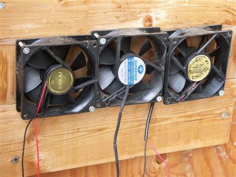 Two Fans Sitting On Top Of A Wooden Wall With Wires Attached To The Fan