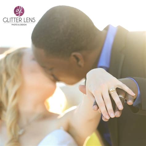 A Bride And Groom Kissing Each Other In Front Of The Sun With Their Wedding Rings