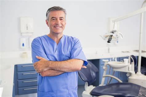 Portrait Of A Friendly Dentist With Arms Crossed In Dental Clinic