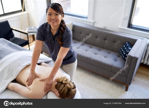 chinese woman massage therapist giving a treatment to an attractive blond client on massage
