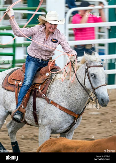 Rodeo Cowgirl And Cowboy On Horseback Competing In Team Calf Roping Or