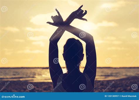 Silhouette Young Woman Practicing Yoga On The Beach At Sunset Stock
