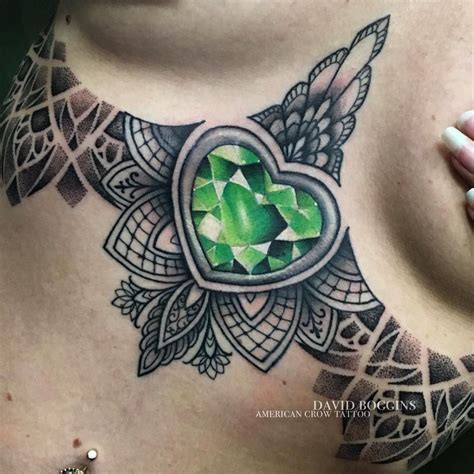 A Womans Chest With A Green Heart Tattoo On It