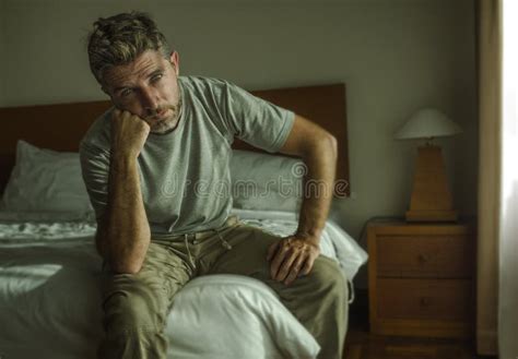 Dramatic Lifestyle Portrait Of 30s To 40s Handsome Man Sitting Sad On Bed Feeling Worried And