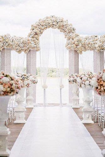 the aisle is lined with tall white vases filled with flowers