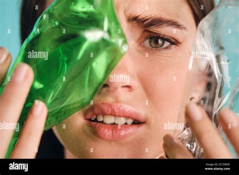 Close Up Girl Covering Face With Empty Plastic Bottles While Sadly