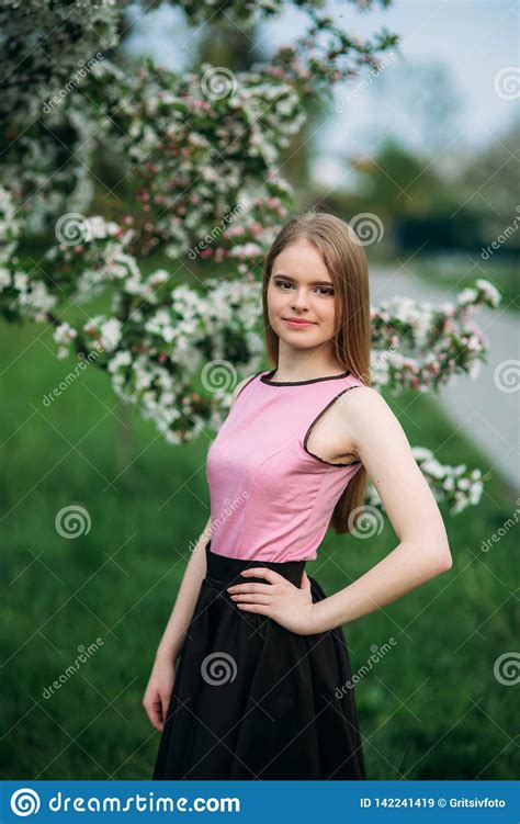 Beautiful Blond Hair Girl Standing In Front Of The Blooming Tree