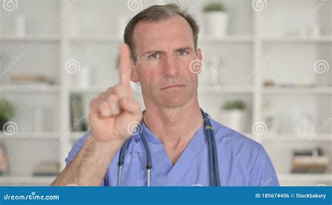 Portrait Of Middle Aged Doctor Saying No With Finger Gesture Stock