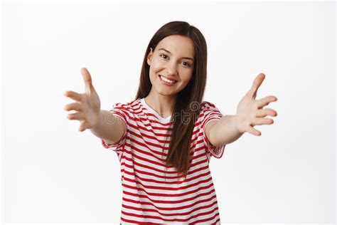 portrait of beautiful 20s girl reaching for hug spread hands sideways and smiling embracing