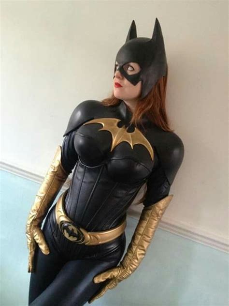 A Woman Dressed As Batgirl Standing Next To A Wall With Her Hands On Her Hips