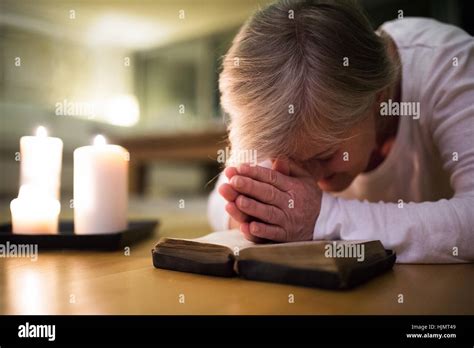 Senior Woman Praying Hands Clasped Together On Her Bible Stock Photo
