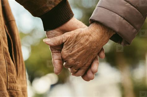 Closeup Of Elderly Couple Holding Hands Showing Gold Wedding By Jessica