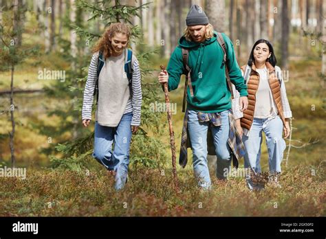 Young People Walking In Forest With Backpacks While Enjoying Hiking