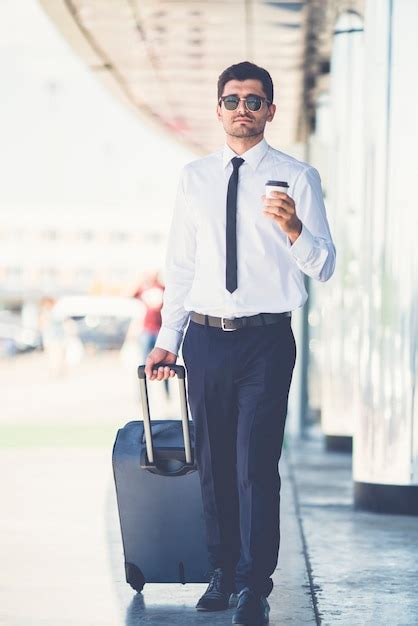 Premium Photo The Businessman In Sunglasses Walk With A Suitcase