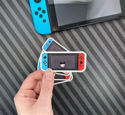 A Hand Is Holding Four Stickers With An Image Of A Video Game