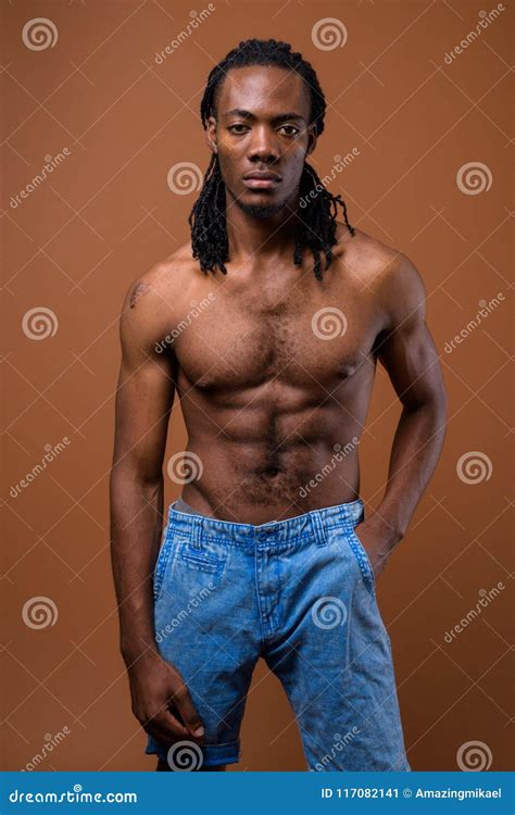Young Handsome African Man Shirtless Against Brown Background Stock