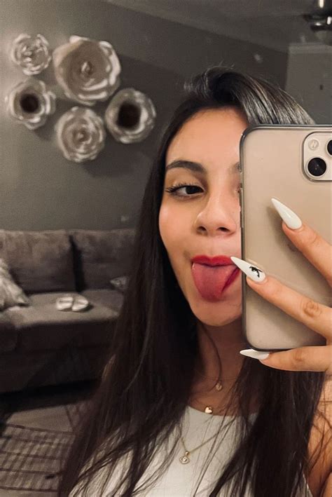A Woman Taking A Selfie With Her Cell Phone And Lipstick Sticking Out The Tongue