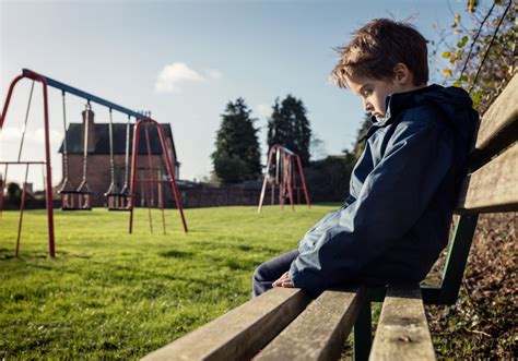 Lonely child sitting on play park playground bench - Sensory Stepping Stones