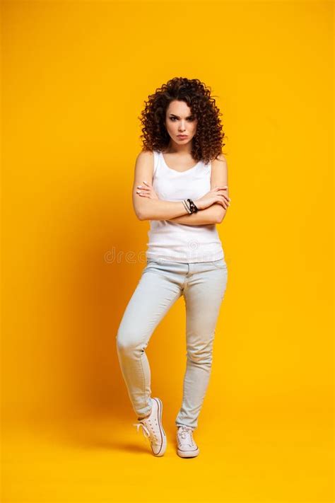 Full Length Portrait Of A Smiling Casual Woman Standing On Yellow