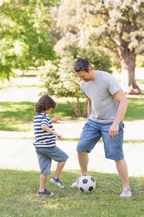 Father And Son Playing Football In The Park Stock Photo By