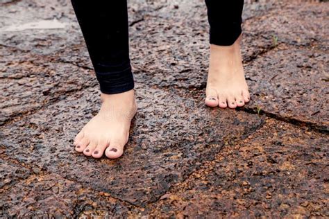 Pies Desnudos De La Mujer Que Caminan En El Pavimento Rocoso Mojado