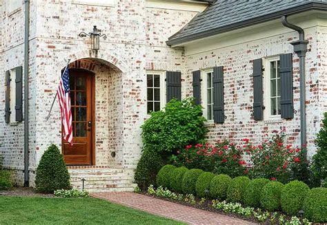 A Brick House With An American Flag Hanging On The Front Door And