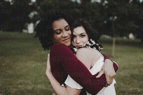Female Friends Embracing At Park Stock Photo
