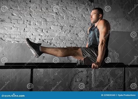Hombre Flexionando Abdominales En Bares Paralelos En El Gimnasio Foto