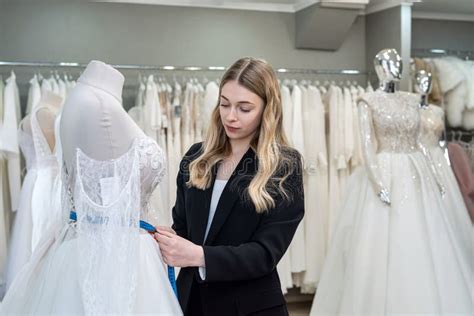 A Pretty Sales Consultant Measures A Wedding Dress For A Client And