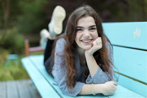 Pretty Seventeen Year Old Girl Lying On Blue Bench Smiling Photograph