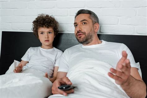 Father Gesturing And Looking At Son Using Digital Tablet Stock Image