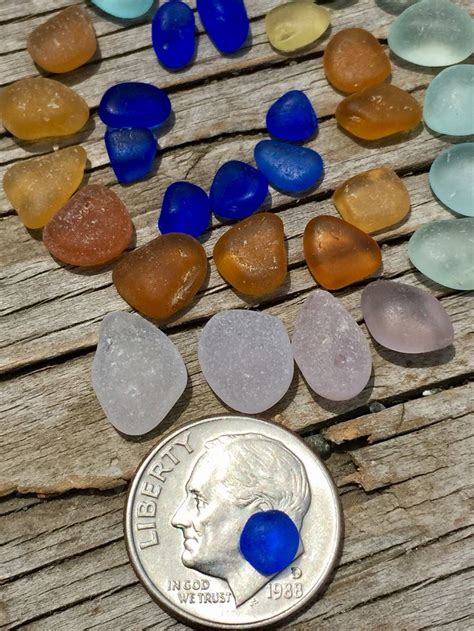 A Penny Sitting On Top Of A Wooden Table Next To Some Sea Glass Pieces And Pebbles