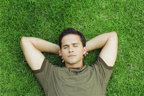 Babe Man Lying On Grass With Hands Behind Head Eyes Closed High Angle View Stock Photo