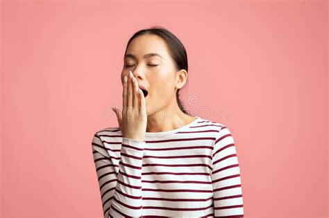 Closeup Shot Of Tired Young Asian Woman Yawning Over Pink Background