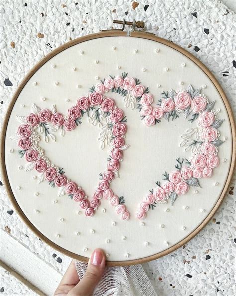 A Hand Embroidered Heart With Pink Roses On It