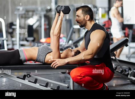 Personal Fitness Trainer Assisting A Young Woman In The Gym At A