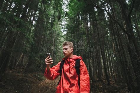 Serious Handsome Young Man In A Red Raincoat Uses A Smartphone On A Hike Concentrated Hiker