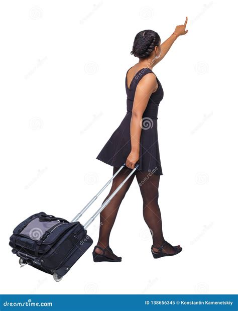 Side View Of A Black African American Walking With A Suitcase And Pointing Hand Forward Stock