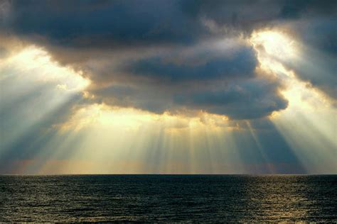Beams Of Sunlight Rays Shining Through Dramatic Clouds Onto The