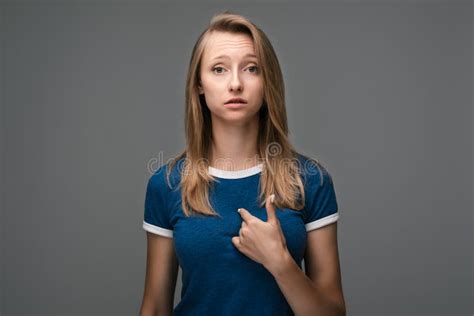 Confused Young Blonde Woman Points At Herself With Forefinger Has