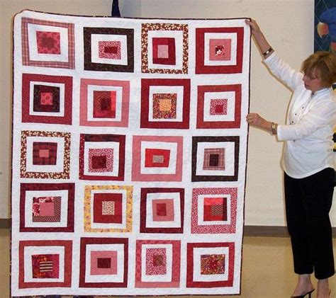 A Woman Is Holding Up A Large Quilt