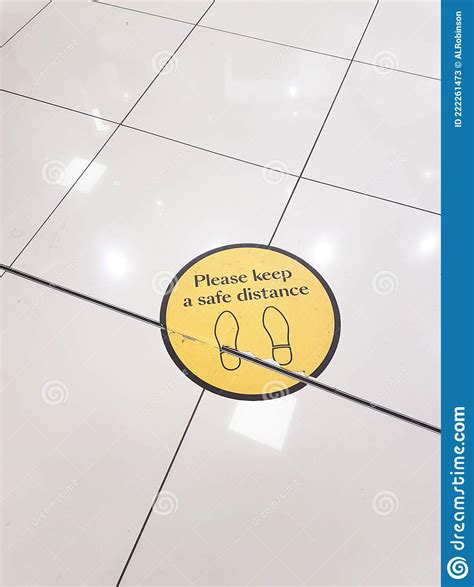 Please Keep A Safe Distance Yellow Floor Sticker On A Tiled Floor