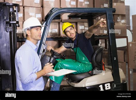 Warehouse manager talking with forklift driver Stock Photo - Alamy