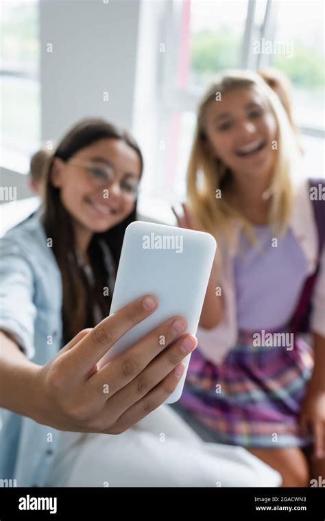 Smartphone In Hand Of Schoolboy Taking Selfie Near Blurred Friends