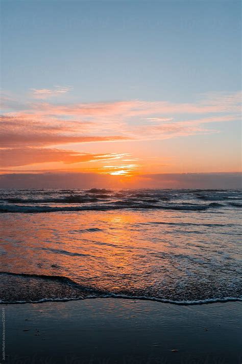 The Sun Is Setting Over The Ocean With Waves Coming In