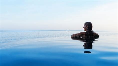 Woman At Edge Of Infinity Swimming Pool With Sea View Stock Image